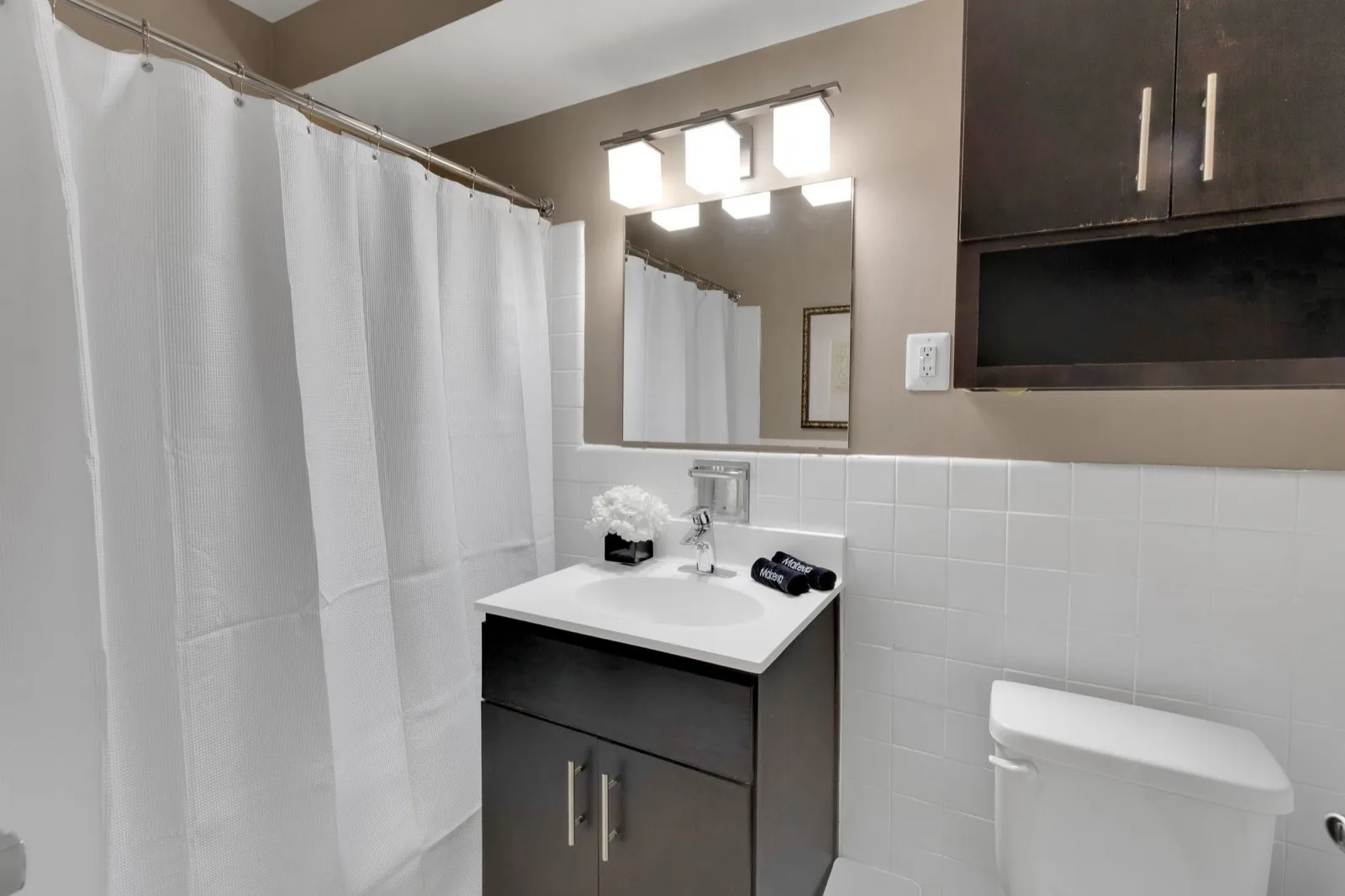 Clean modern bathroom with a dark vanity and white tile in a Crystal City furnished apartment