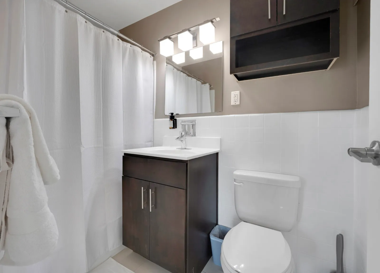 Clean bathroom with white tile, a dark vanity, and chrome fixtures in a Crystal City furnished rental