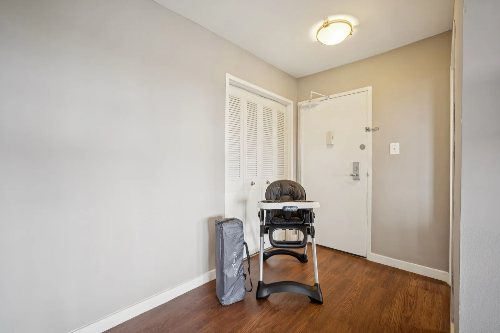 Entry foyer set up with a high chair and Pack-'n-Play for a family-friendly furnished apartment in Arlington VA