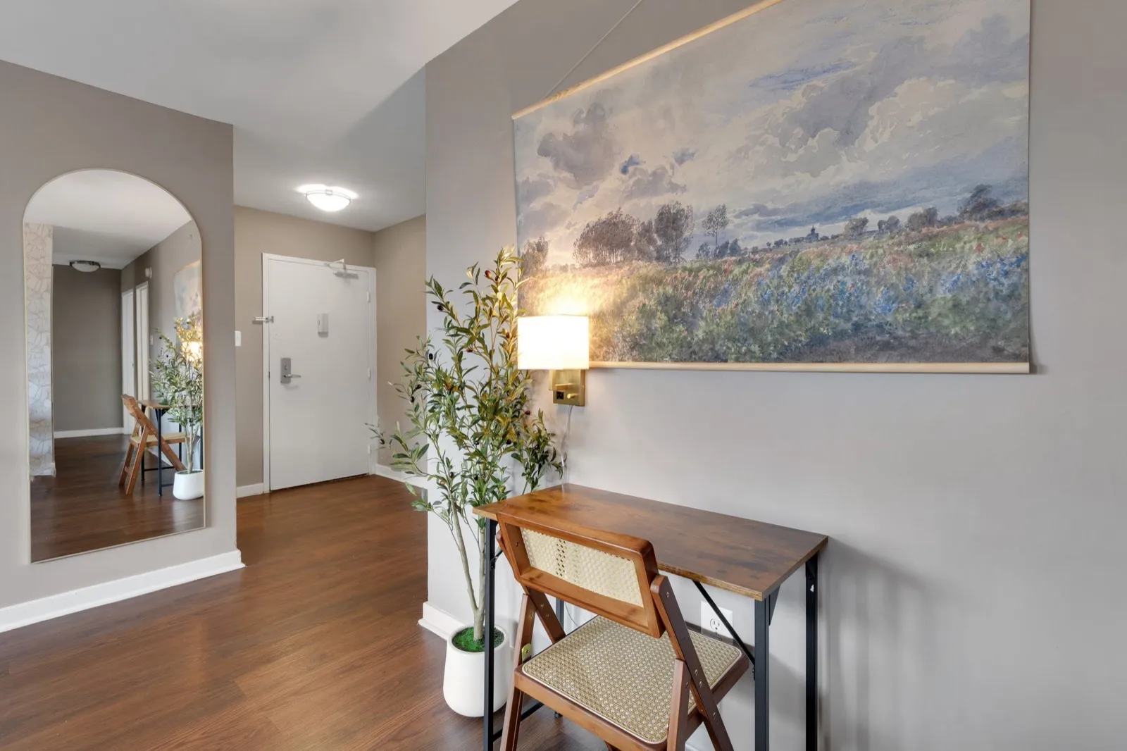 Welcoming entry foyer with a work desk, landscape artwork, and hardwood floors in an Arlington VA furnished apartment