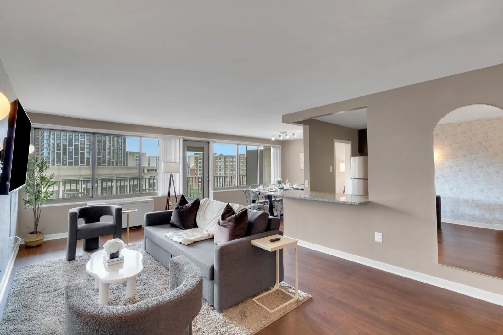 Open furnished living room with sectional sofa and floor-to-ceiling windows over National Landing, Arlington VA