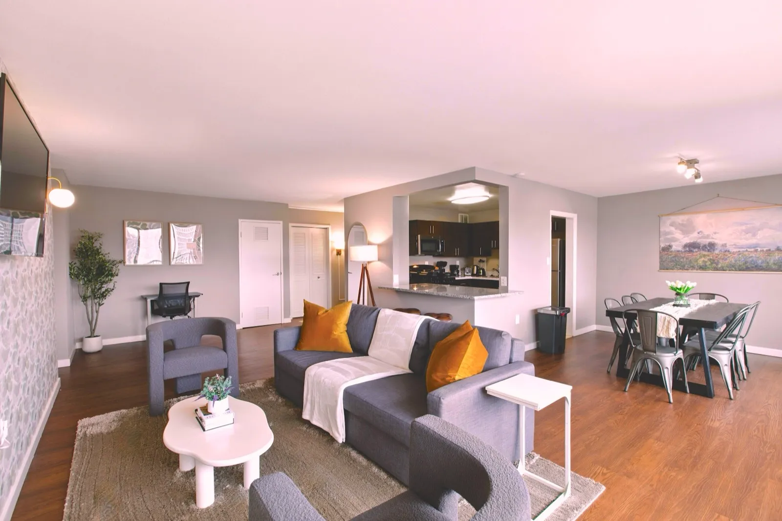 Open living and dining area with a modern sofa, gold accent pillows, and framed wall art in an Arlington VA furnished apartment