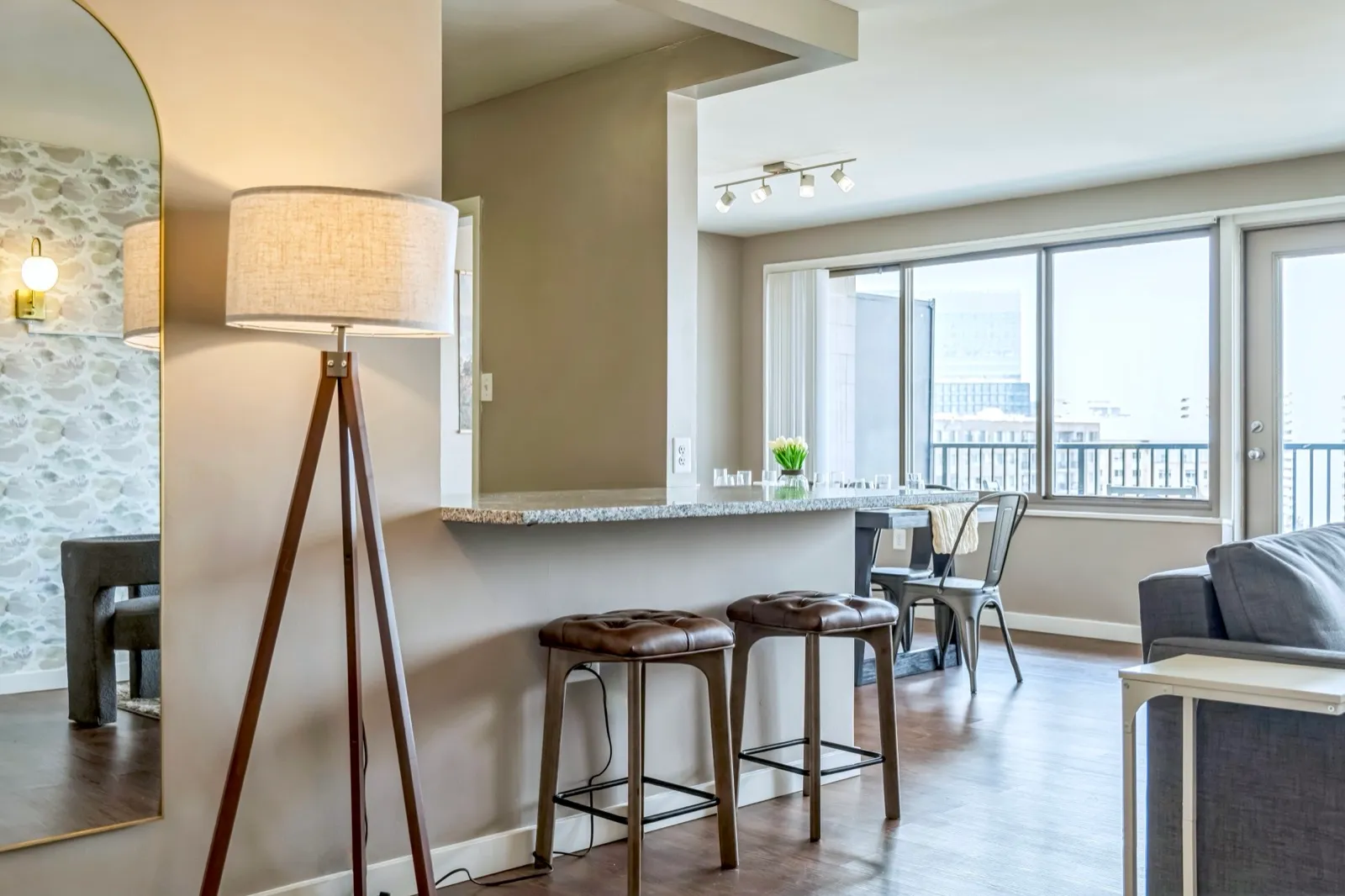 Open-concept living room with a breakfast bar and stools framing city views in a Crystal City furnished apartment
