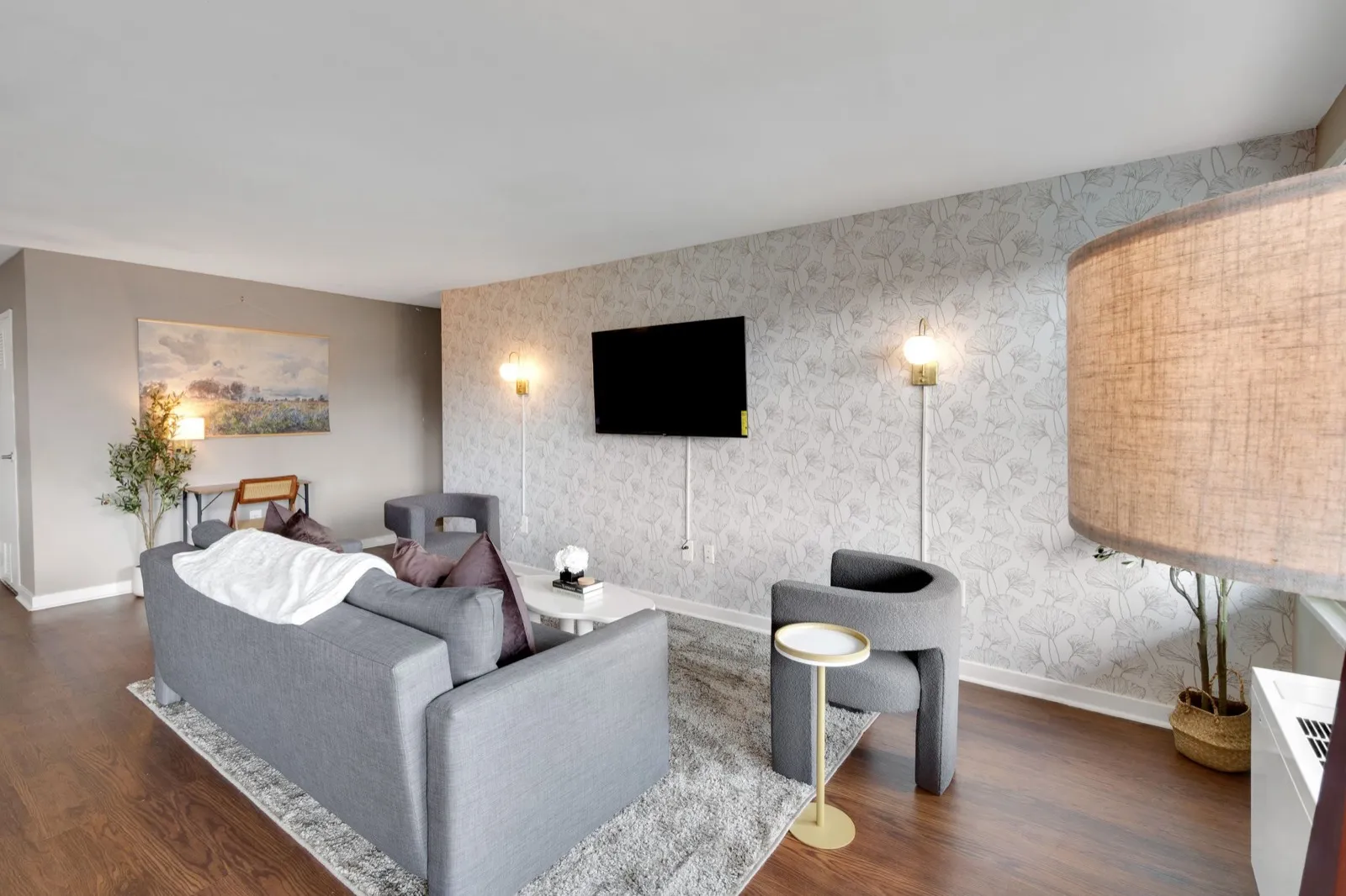 Open-concept living room with sofa, accent chairs, and botanical wallpaper in Crystal City