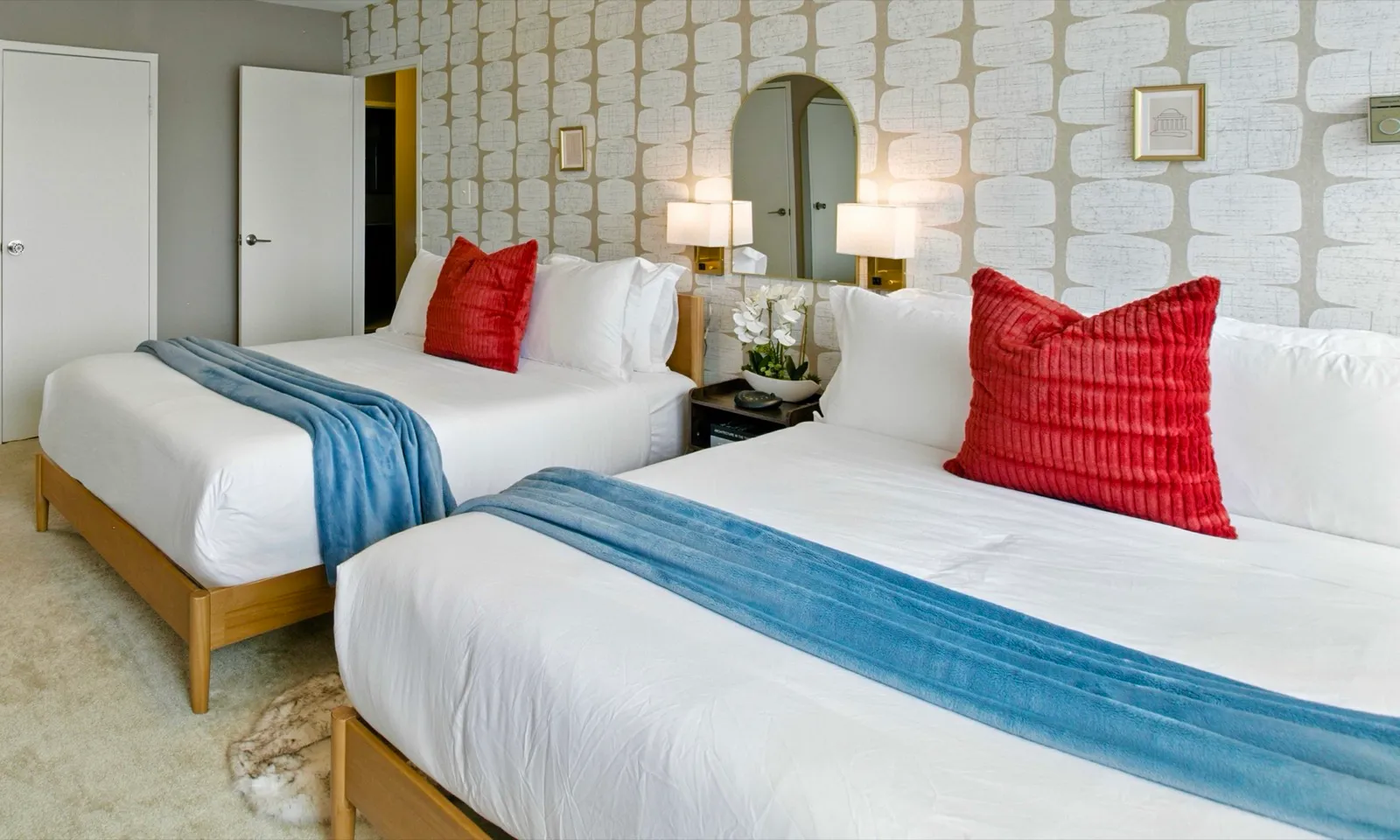 Guest bedroom with two beds, geometric wallpaper, and an en-suite bathroom in a Crystal City furnished apartment