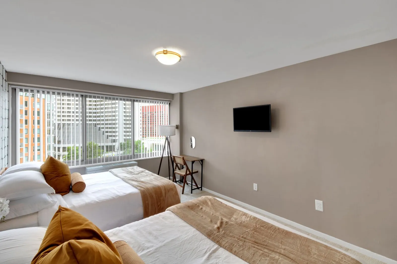 Second bedroom with two beds, warm earth tones, and a work desk by the window, Crystal City furnished rental
