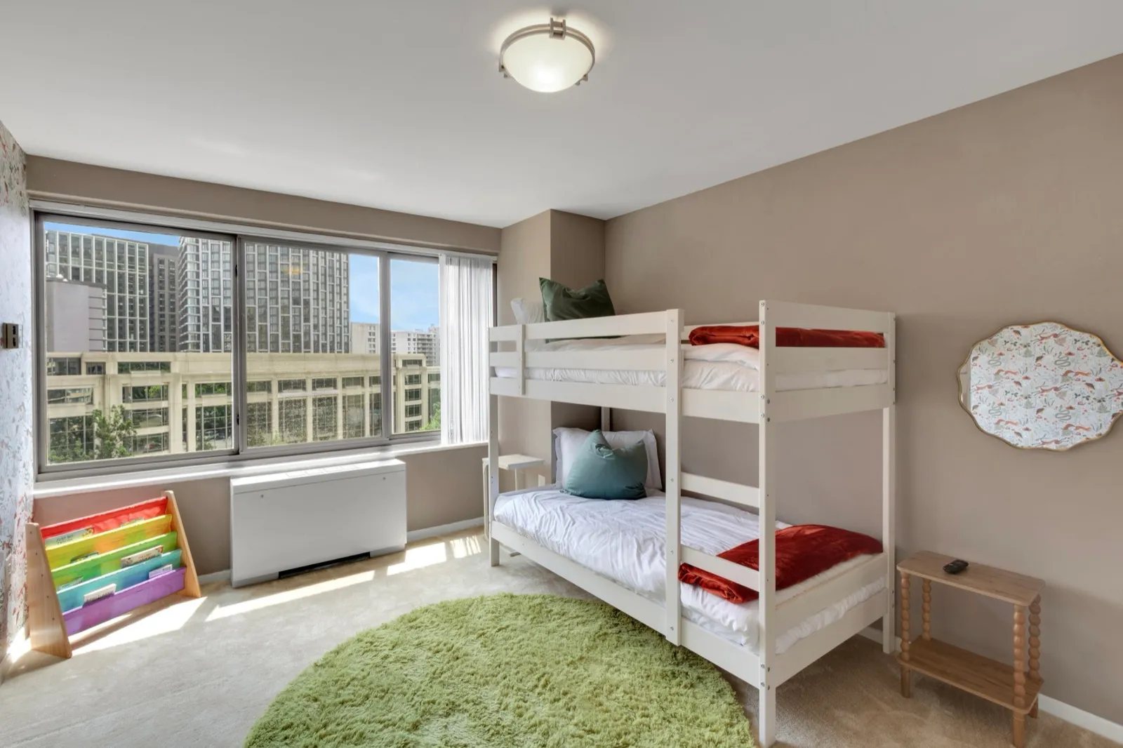Kids' room with twin bunk beds, a rainbow book rack, and a soft green rug — family-friendly furnished apartment in Arlington VA